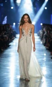 Confident female model walking runway in embroidered maxi dress at glamorous fashion show, spotlight on intricate details